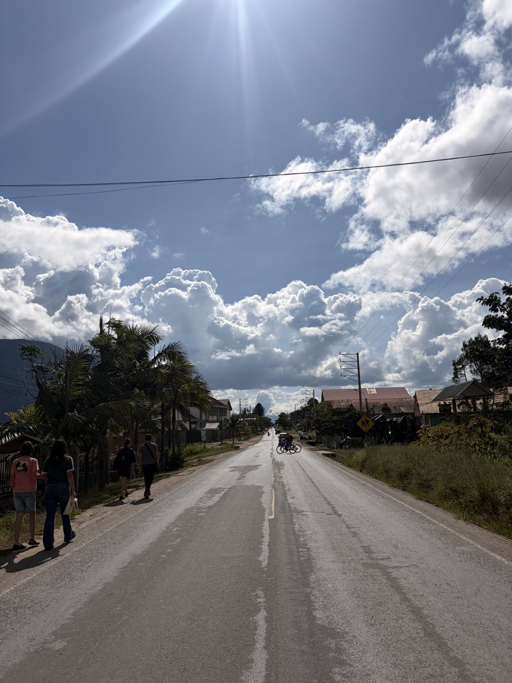 Carretera bajo un cielo abierto con nubes y luz del sol.